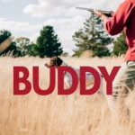 Hunting Dog Buddy stands alert in a field of tall grass.