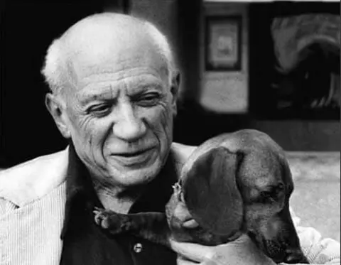 A black and white photo of Pablo Picasso holding his dachshund, Lump, prompting the question: Who is the most famous Dachshund?